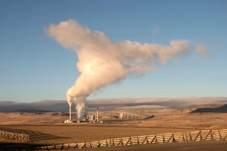 Smoke rising from chimney of power plant in barren landscape