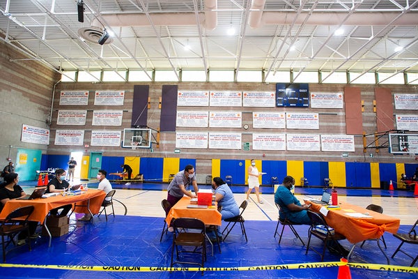 Healthcare workers at tables in a sports complex