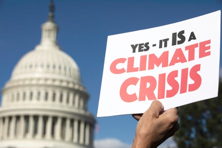 A hand holds a sign stating "Yes, it IS a Climate Crisis" during a climate change protest on Capitol Hill in Washington, D.C.