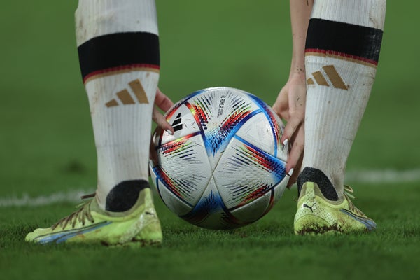 A view of a soccer ball on the ground between a player's feet.