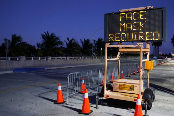An illuminated sign by a roadway says "Face Masks Required."