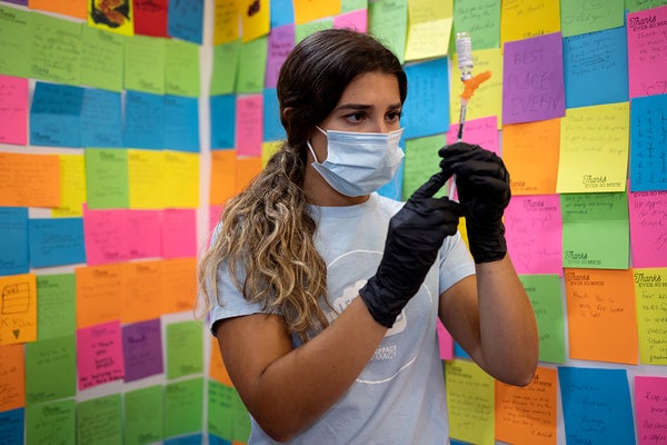 Health care worker holds syringe and is surrounded by colorful sticky notes