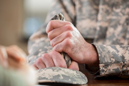 Man wearing military uniform holding a piece of cloth tightly with both hands.