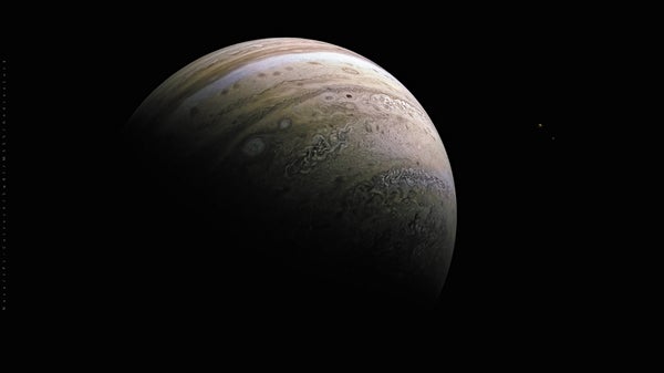 View of Jupiter's Moons Io (large at left) and Europa (very small at right), shown against a black background.