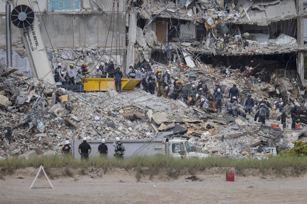 Rescue workers search in rubble of collapsed apartment building.