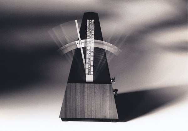 A pyramid-shaped device with a vertical arm swinging back and forth, forming a blur.