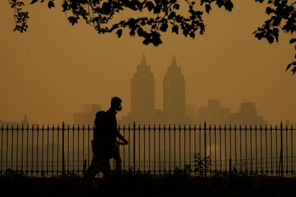 Silhouette of person walking against smoke-filled sky