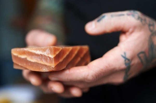 Close-up of hands holding a salmon filet that looks like real fish but is made of plant-based ingredients