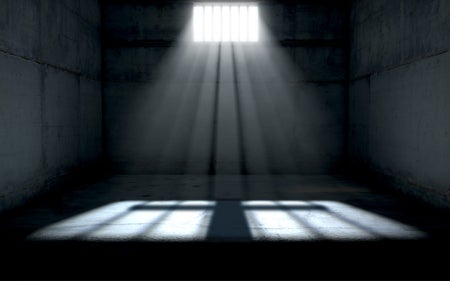 Dim sunlight shines into a dark prison cell.
