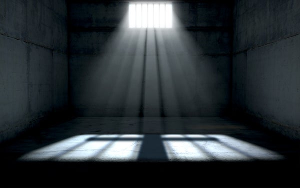 Dim sunlight shines into a dark prison cell.