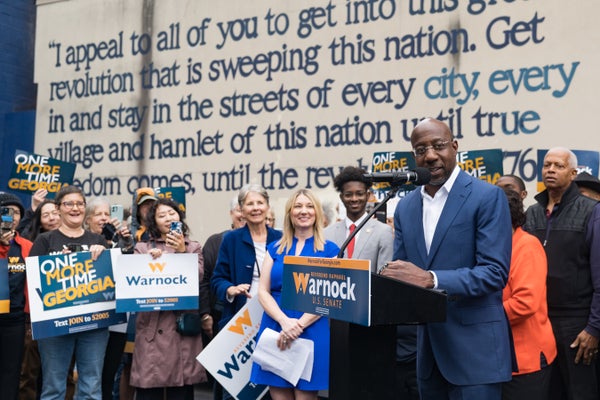 Sen. Raphael Warnock (D-GA) speaks at a press conference surrounded by young supporters