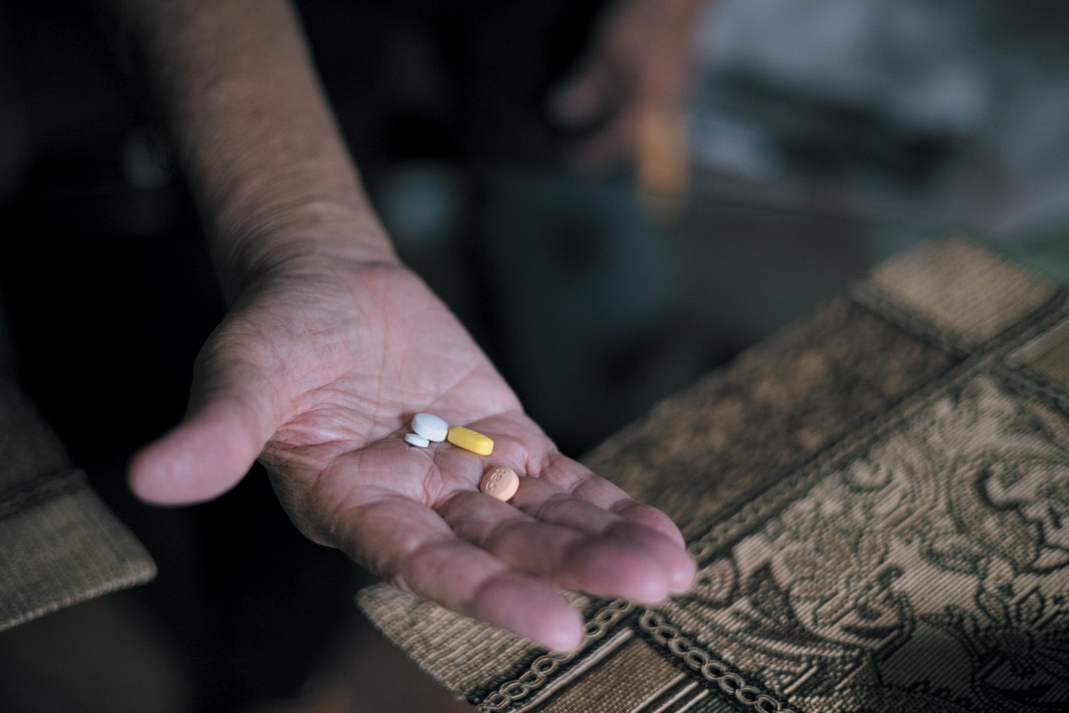Man holding handful of pills.