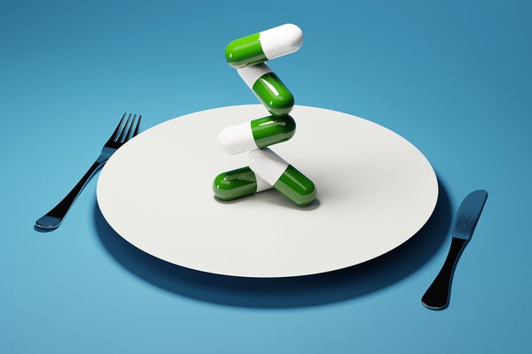 pills stacked on dinner plate, fork and knife on sides of plate, blue background