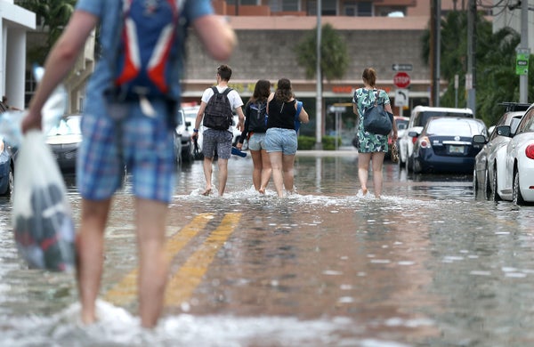 People walk through a flooded street in Miami Beach.