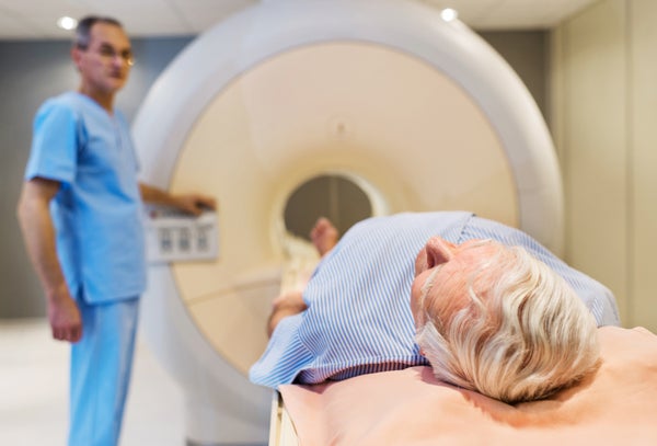 Senior man receiving an MRI Scan with doctor in the background