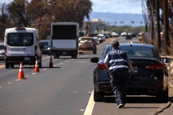A Federal Emergency Management Agency (FEMA) walking behind a car in Maui after wildfire.