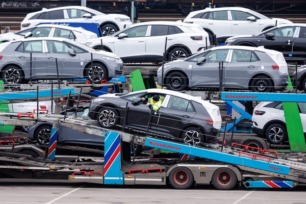 Different colors of VW electric cars being unloaded off a ramp.