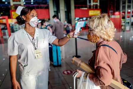 A nurse checks the temperature of a woman at the airport.