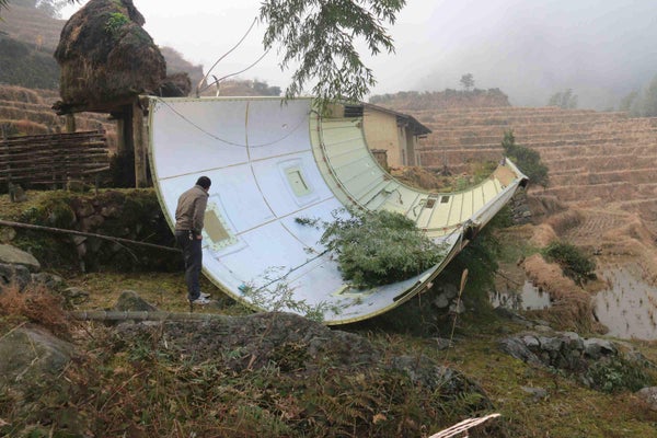 A person in a field inspects debris from fallen spacecraft