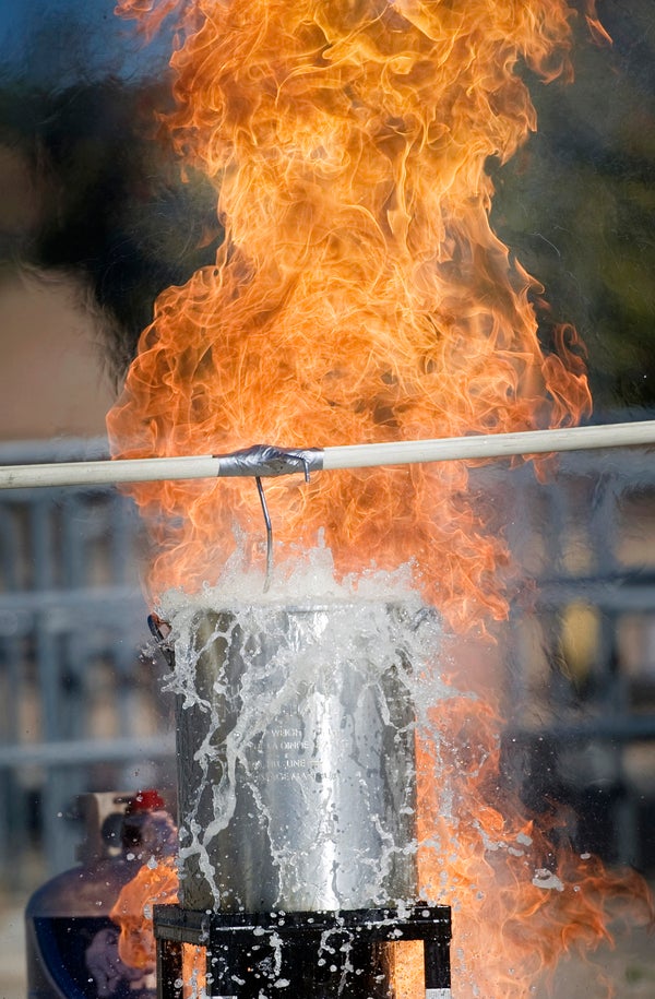 A hanging metal bucket with flames in the background
