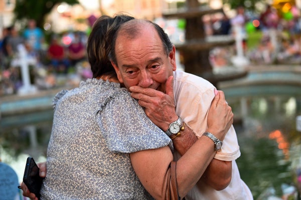 A woman embraces a man overcome by emotion at a memorial