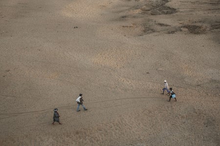 Aerial view of people crossing dried-up river bed.