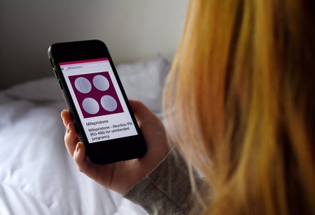 A person looks at an Abortion Pill (RU-486) for unintended pregnancy from Mifepristone displayed on a smartphone