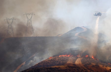 Helicopter flies through heavy smoke above wildfire