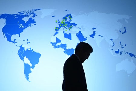 Silhouette of John Kerry on stage with world map behind him.