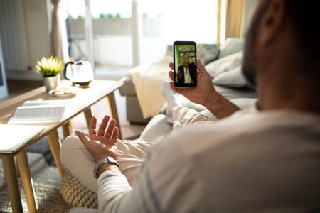 Close up of a mid adult man using his smart phone to talk to his therapist