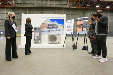 Kamala Harris and Jennifer Granholm listen to presentation in airplane hangar