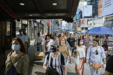 Pedestrians in the Times Square, some wearing face masks and some without