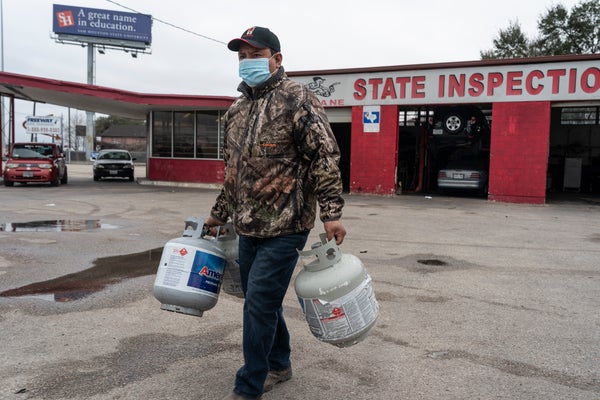 A person carries empty propane tanks, bringing them to refill at a propane gas station after winter weather caused electricity blackouts on February 18, 2021 in Houston, Texas.