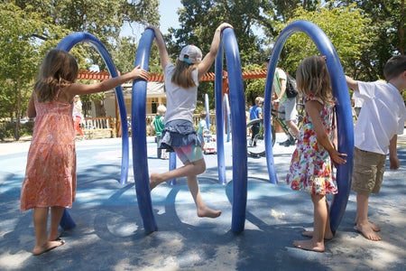 Children play on giant blue rings on a playground.