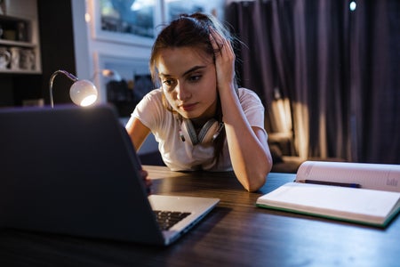 Teen girl at a computer at night.