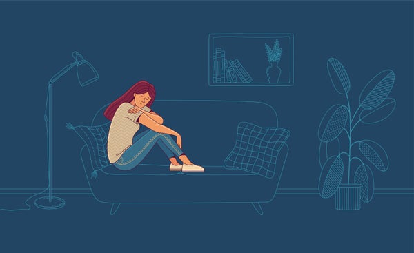 Young woman sitting on sofa in room at night