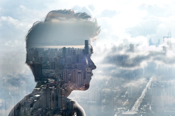 A double exposure of a young man looking out over a cityscape into the clouds