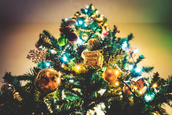 Close up of heavily decorated christmas tree with golden ornaments and golden background.