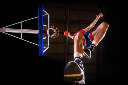 Below view of a basketball player slam-dunking the ball