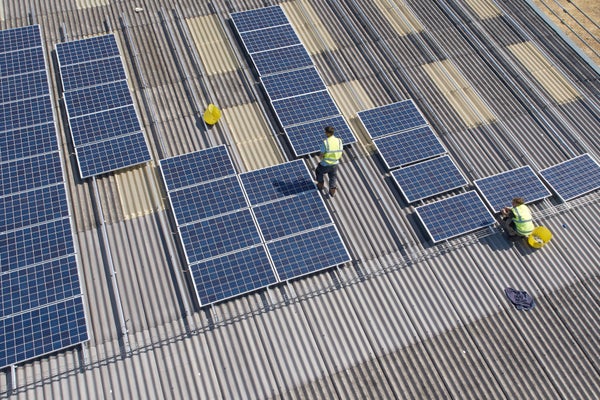 Two men installing solar panels on rooftop