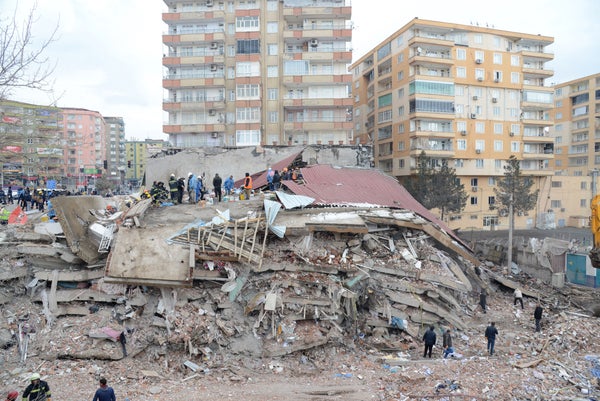 Rescue workers and volunteers search for survivors in the rubble of a collapsed building