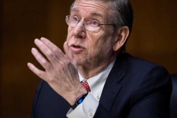 An older man gestures while talking.