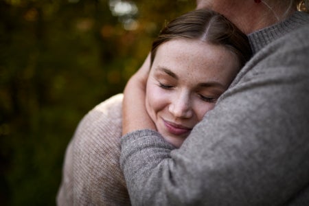 Grandmother embracing adult granddaughter in garden