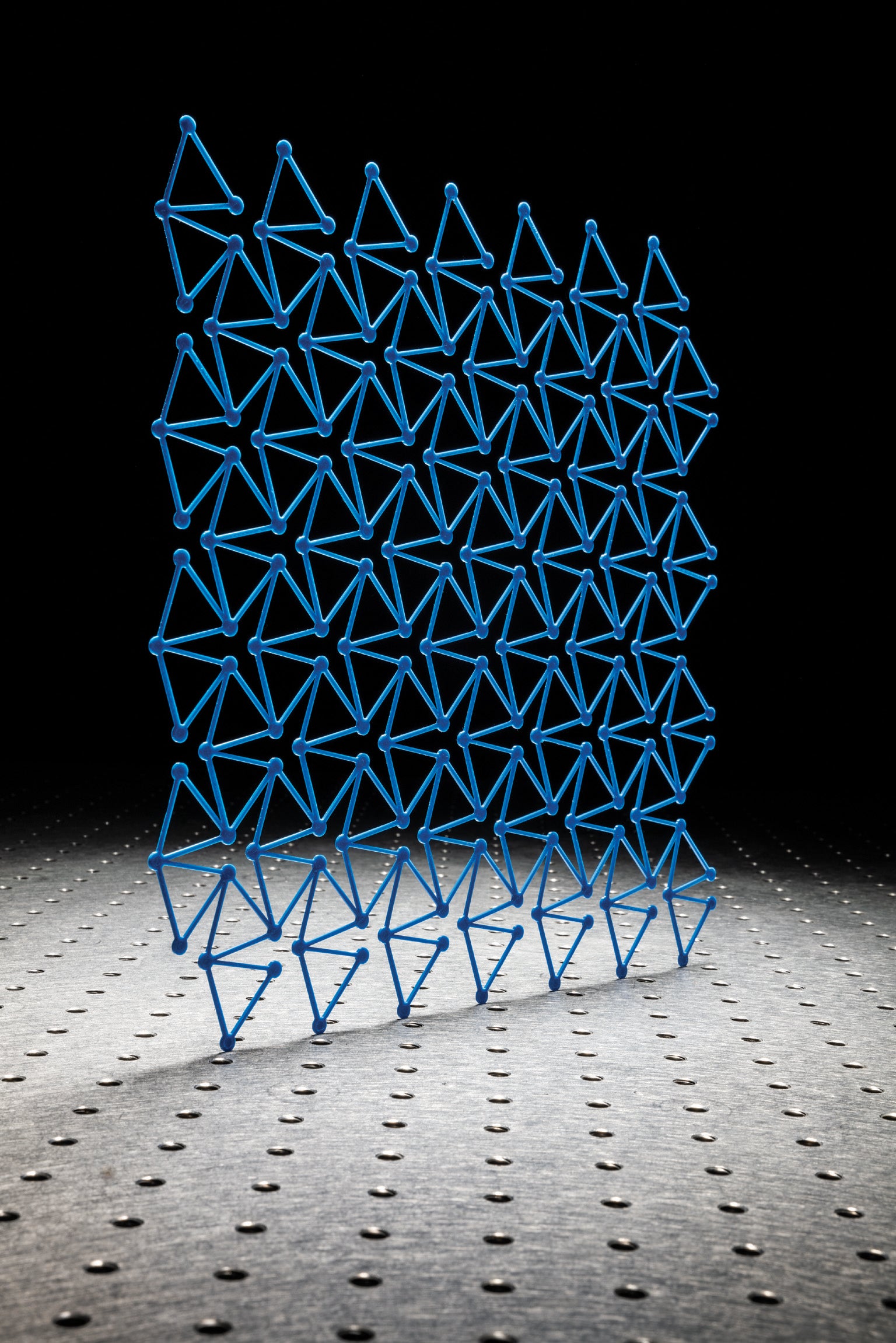 Metasurface for elastic waves. Blue triangles against dark background.