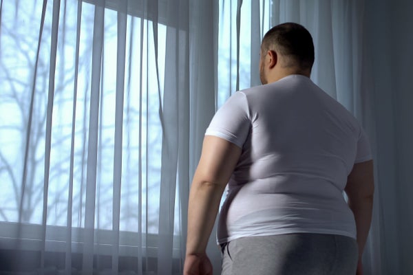 Overweight man looking out window.