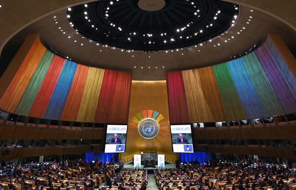 Delegates sitting under dome with rainbow color backdrop behind United Nations Secretary-General Antonio Guterres speaking at the opening session of the second Sustainable Development Goals (SDG) Summit.