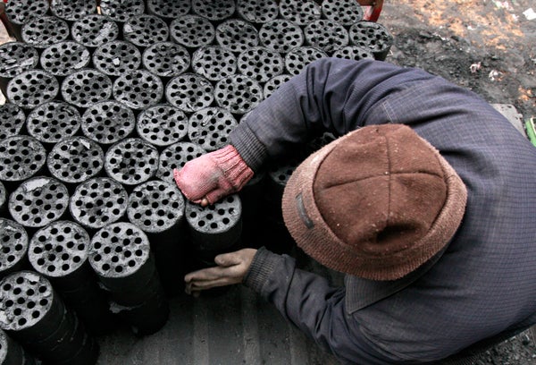 Overhead view of worker moving coal briquettes onto a pedicab.