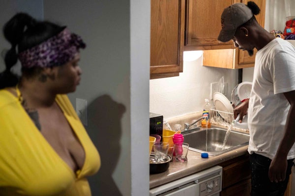 A woman watches man our bleach into kitchen sink