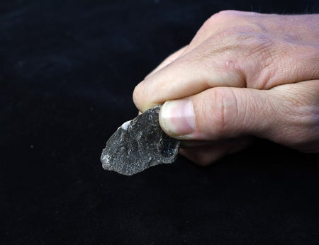 A hand grasps a stone flake.