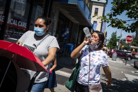 Two pedestrians walking down the street during a heatwave in the Brooklyn borough of New York, U.S.